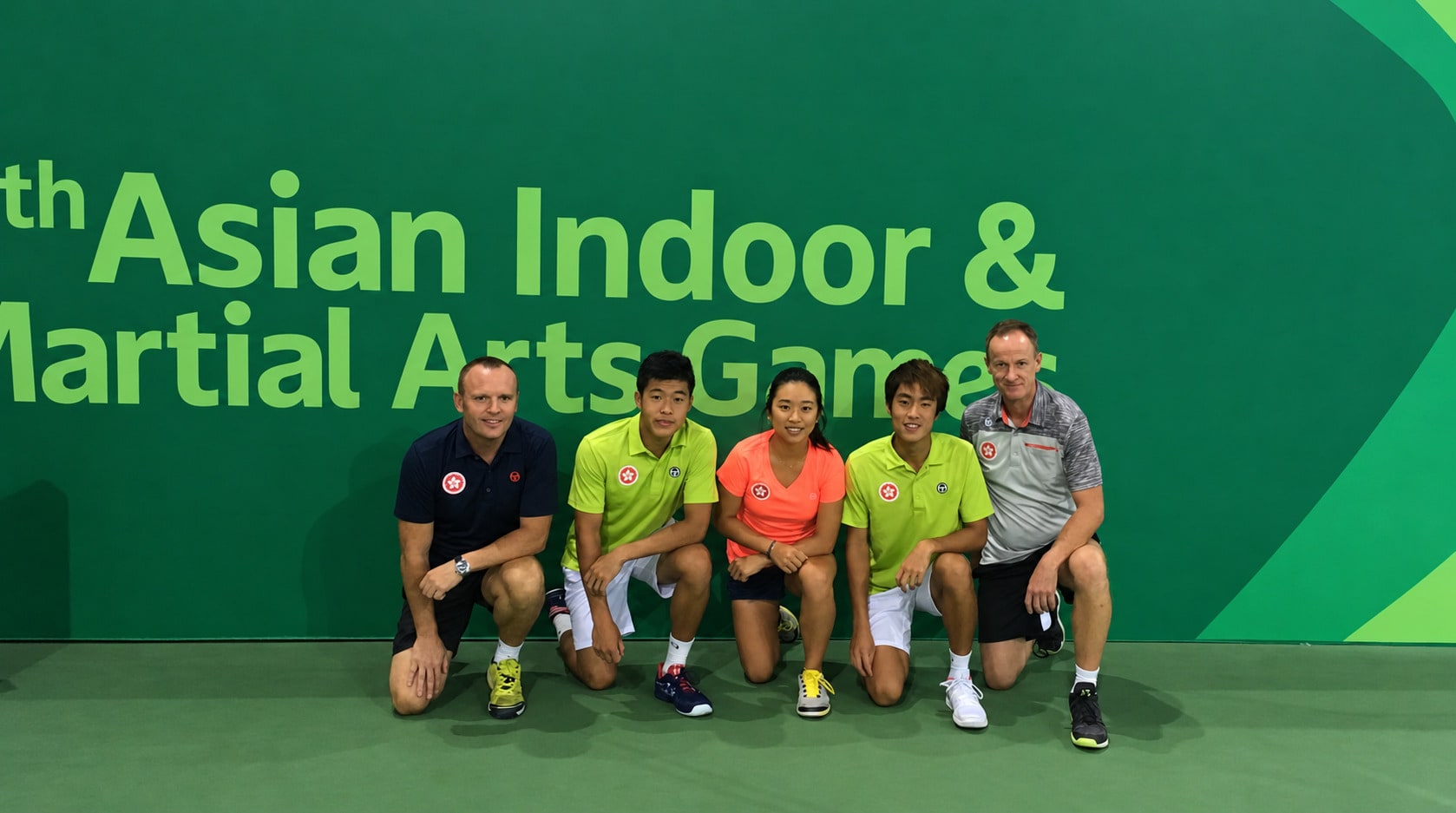 Jeff King kneeling with the Hong Kong tennis team at the Asian Indoor & Martial Arts Games.